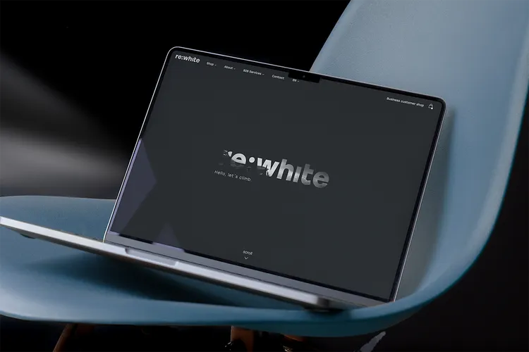 A laptop with a black website interface shows the logo 'rewite' on a blue chair. The screen text reads: 'Hello, let's climb.'