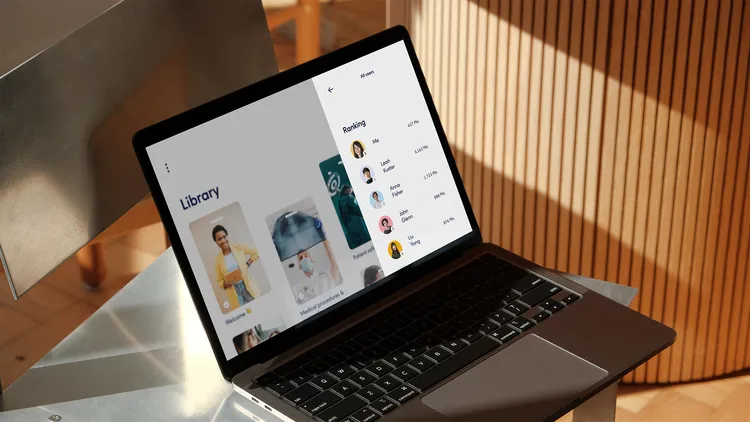 A laptop on a metal table displays an interface labeled 'Library'. On the left, images of people are visible, while on the right, there is a list of names and times. Sunlight shines on the table.