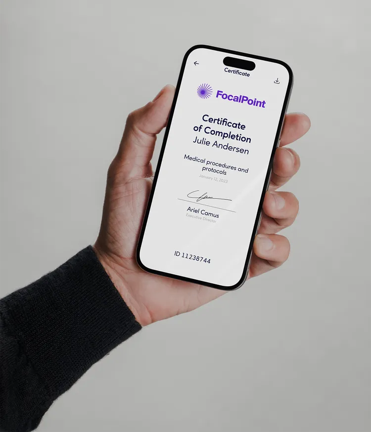 A hand is holding a smartphone displaying a certificate from 'FocalPoint'. The certificate is for Julie Andersen for completing 'Medical procedures and protocols' dated January 12, 2023. Below is the name Ariel Camus as Executive Director, with a signature and ID 11238744.