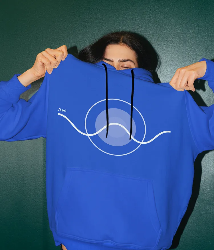 A woman wearing a medium blue hoodie with Aeri app UI artwork and logo.