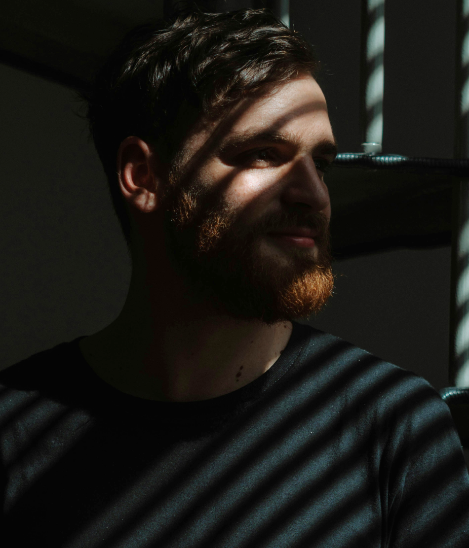 A man in the light and shadow of a striped architectural structure.
