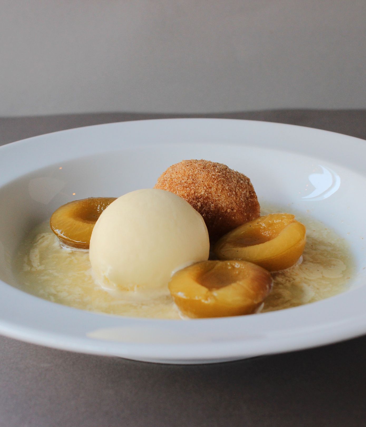 Ein Gericht aus der Küche Maquis mit Krapfen, Eis und flambierten Pflaumen.
