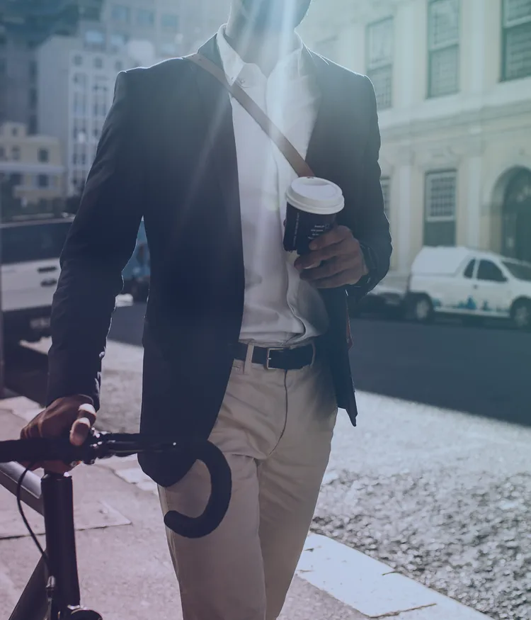 Male office worker pushing his bike and drinking take away coffee