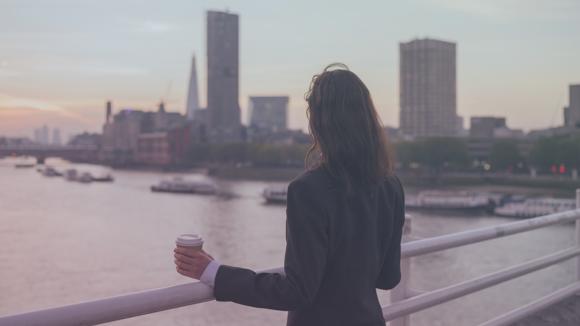 Female office workers standing on bridge and looking at the city skyline