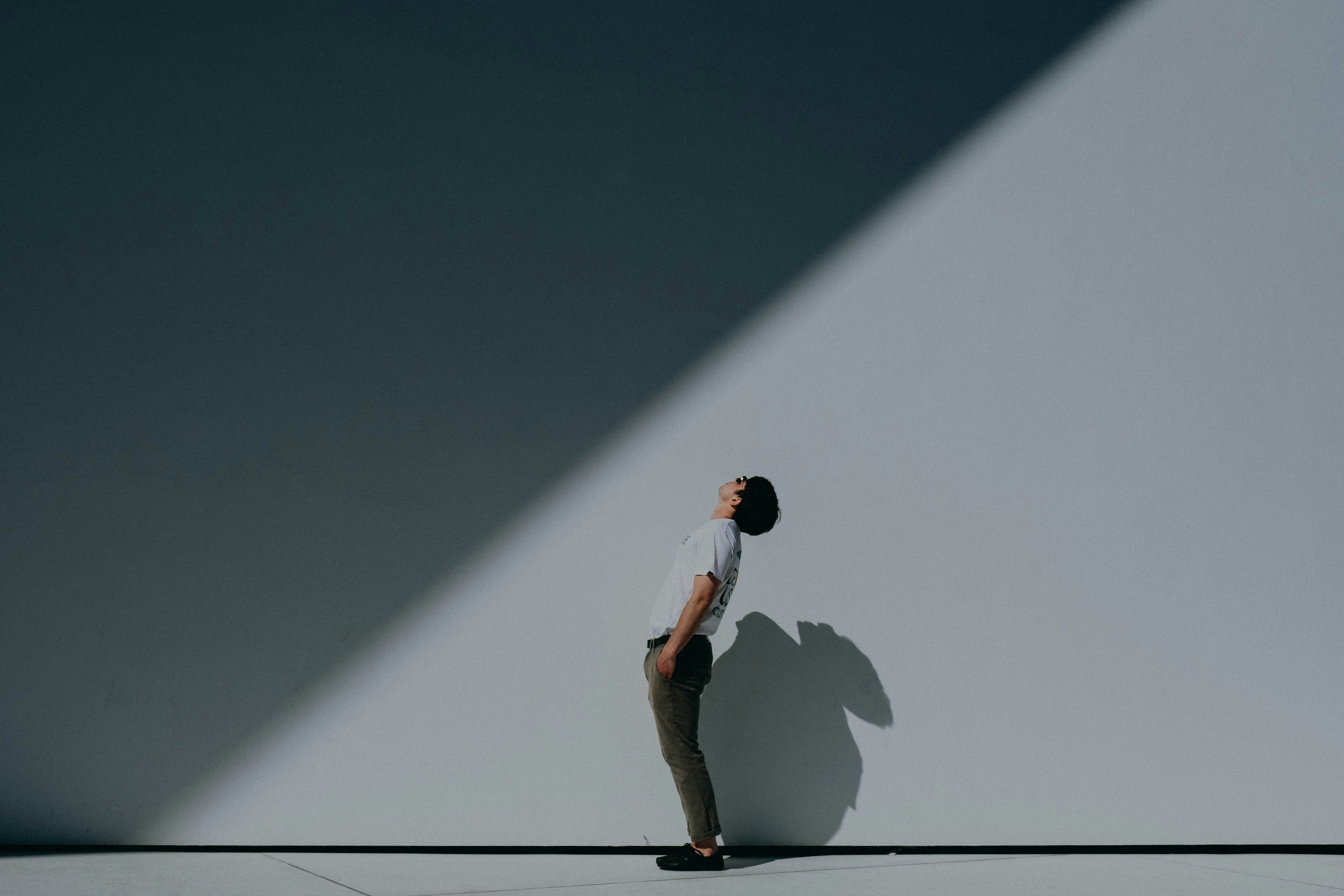 Man bending backwards and looking at shadow on wall hanging over him