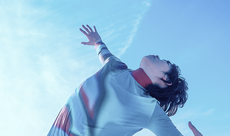 Person tanzt under blauem Himmel