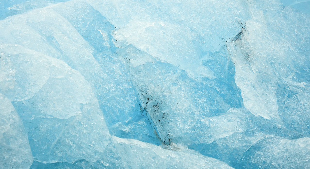 Close-up of bright blue ice with textured surfaces, featuring cracks and varying shades.