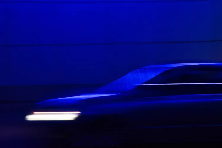 A blurred image of a moving car in a tunnel with blue lighting. The car's headlights create streaks of light.